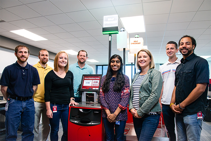 Rilee and seven teammates stand around one of their self-checkout test machines