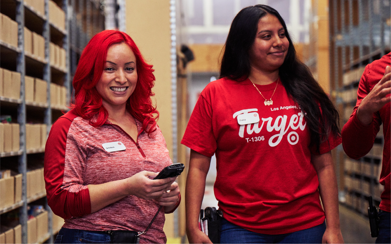 Two team members smile and walk down an aisle.