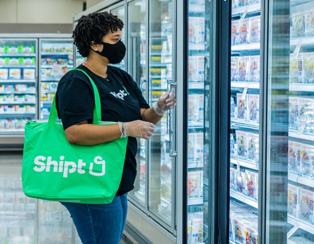 a person wearing a mask and holding a green bag