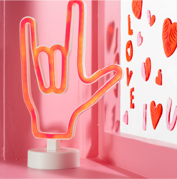 A neon sign with a hand making the American Sign Language sign for "I love you."