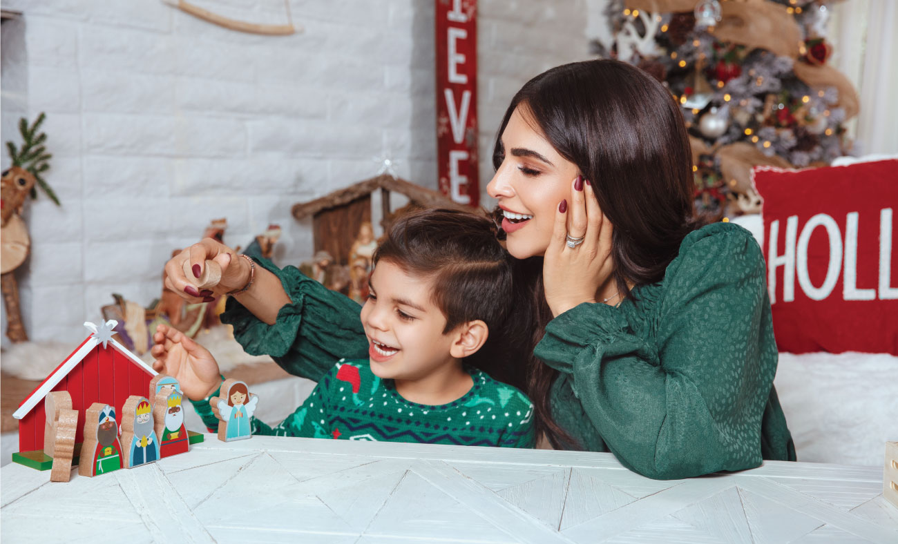 Alejandra and her son play with a wooden manger scene.