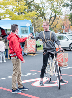 A team member delivers bags to a guest on a bike in the Drive Up space