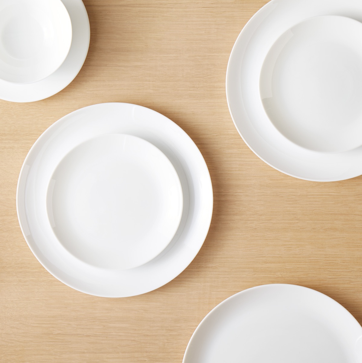 White, round dinner plates with white bowls stacked on top