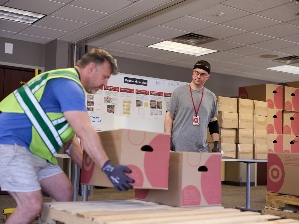 One Target team member trains on how to correctly lift a heavy box, while another team member observes.