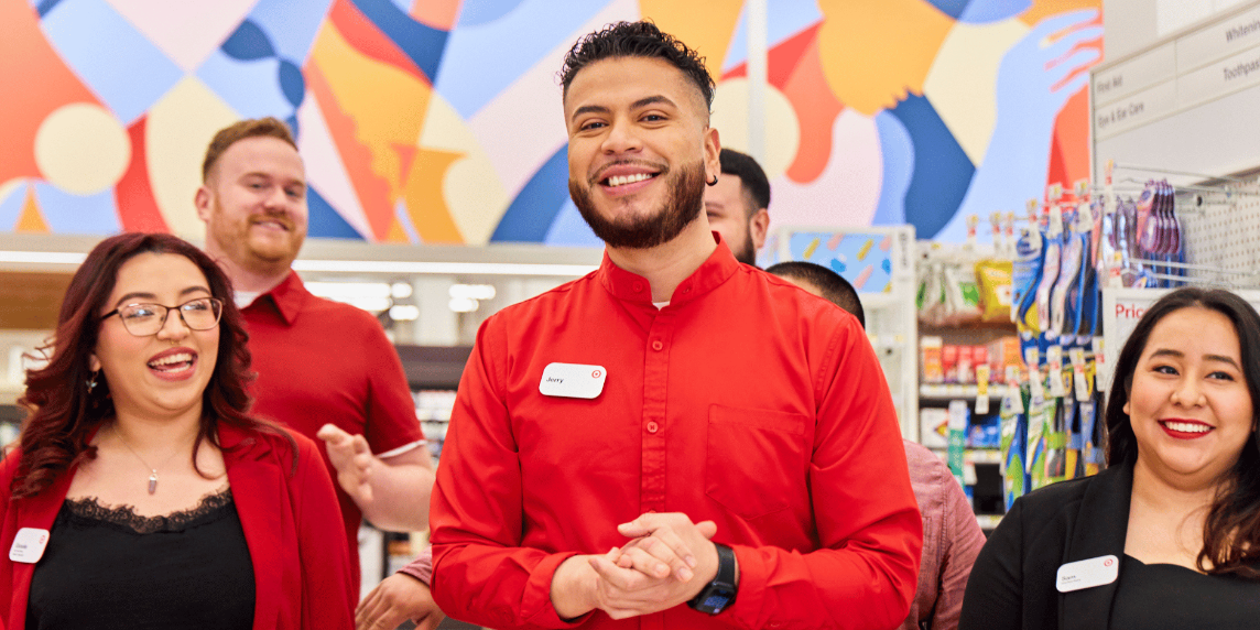 Six people smile as they stand in a Target store wearing red and black.