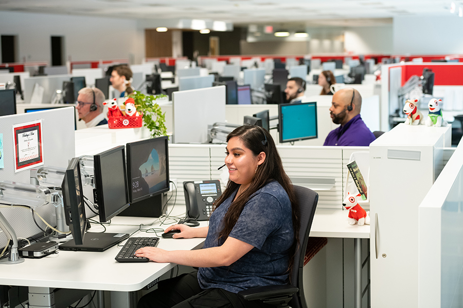 Team members sit in cubicles working on computers and speaking to guests on headsets