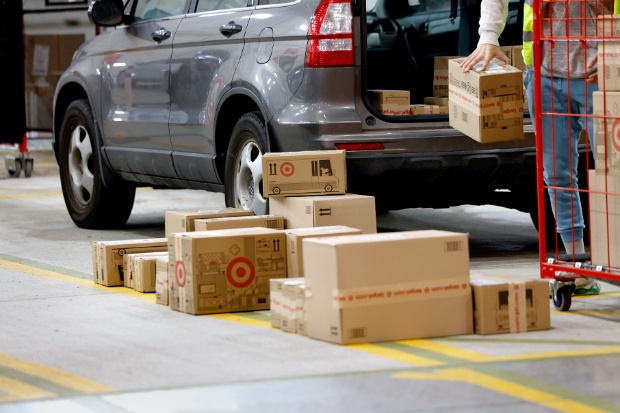 A pile of boxed guest orders sits behind a driver’s vehicle, ready to be loaded.