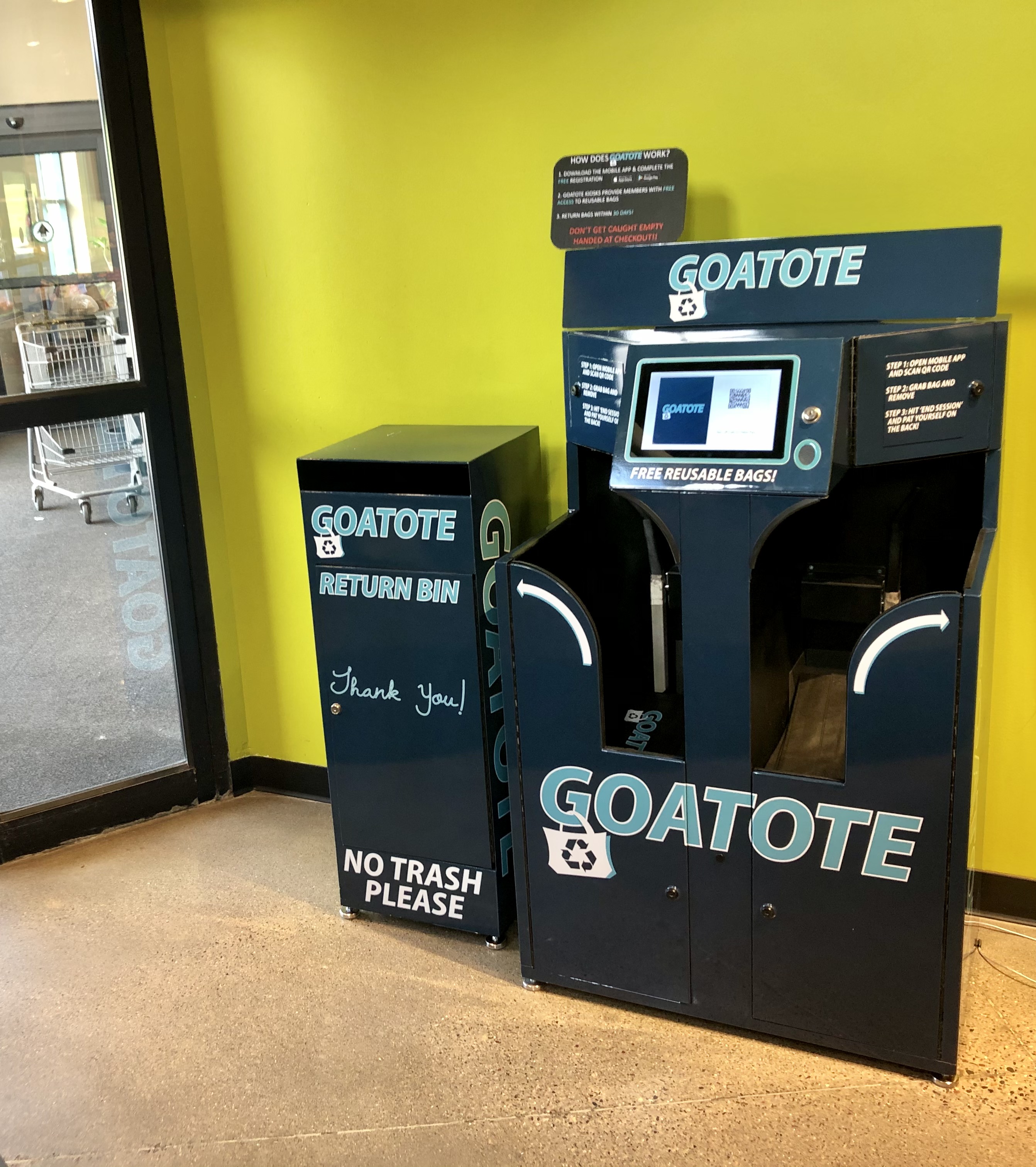 In the entryway of a store, a collection box and a kiosk are labeled GOATOTE