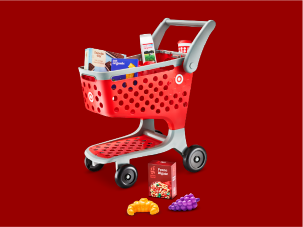 The Target Toy Shopping Cart with pretend food in the cart and on the ground next to the cart.