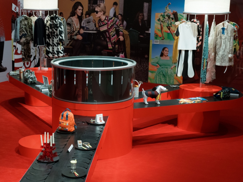 Hero image with the text “Guest Experience: Inside Target’s Next Chapter of Great Design for All” beside a vivid red Target by Design exhibit at New York City’s New Museum, featuring circular display structures, a long black platform lined with curated objects, fashion imagery and colorful products throughout the space.