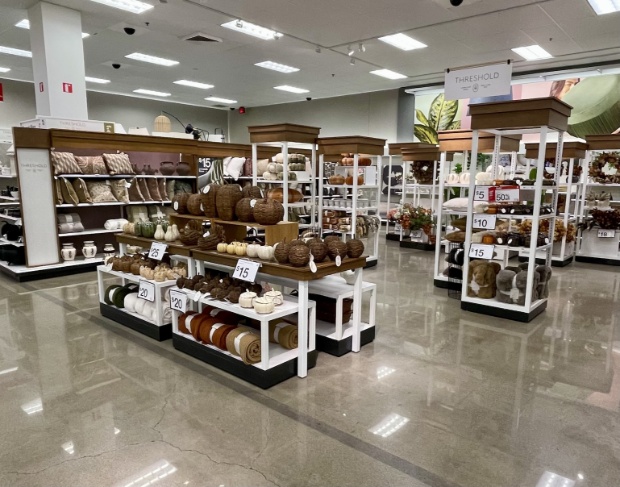 Pumpkin-shared décor items made of wicker and autumnal throw blankets on white retail display shelving.