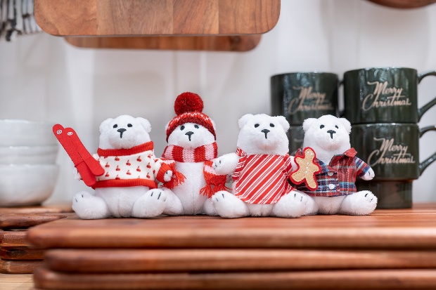 Four mini plush Berry the Bears are seated on a stack of cutting boards.