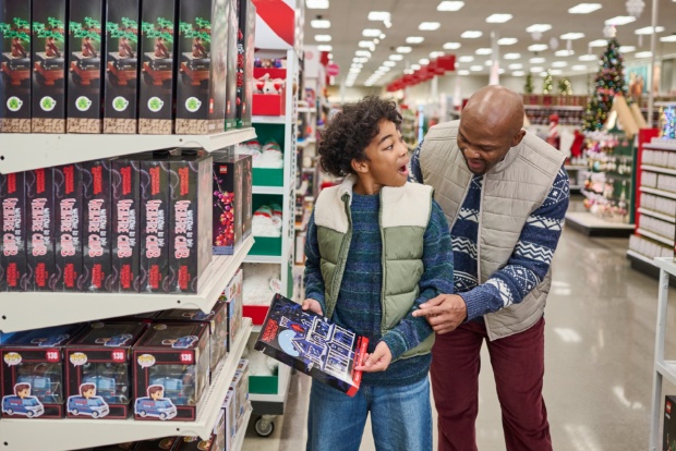 A toy aisle featuring LEGO sets and holiday décor, with shoppers browsing shelves.