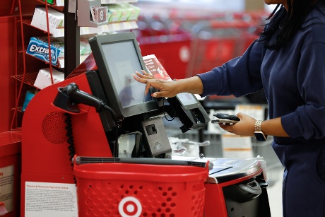 A guest at a self-checkout station touches the screen while making a purchase.