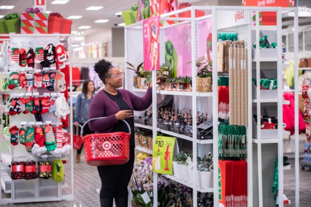 A guest carrying a red Target basket browses colorful holiday displays.
