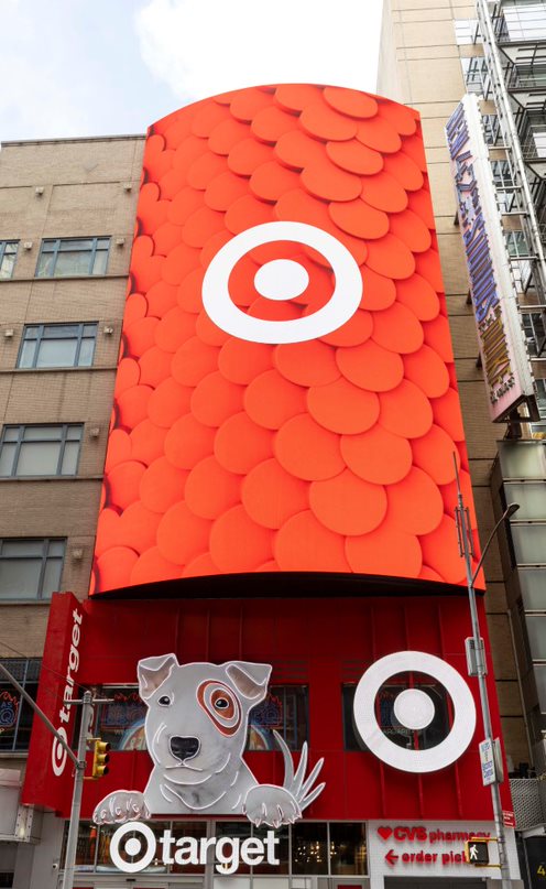 The front of a building has a large screen with a white bullseye logo on a red background, a white dog and white bullseye and Target logos.