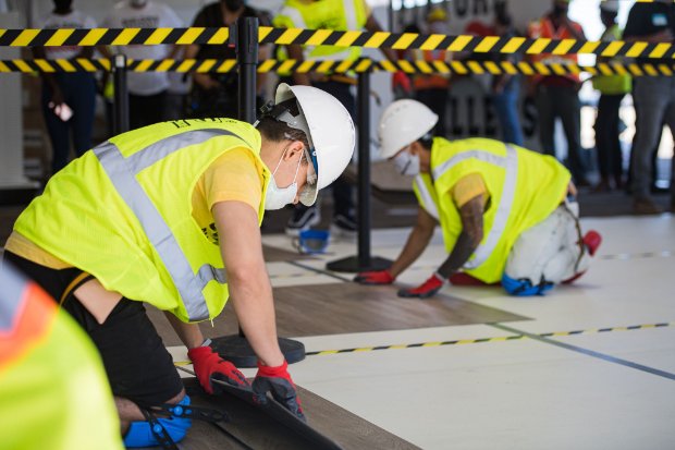 a group of people wearing helmets and working on a piece of wood