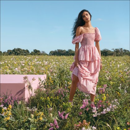 a woman in a pink dress standing in a field of flowers