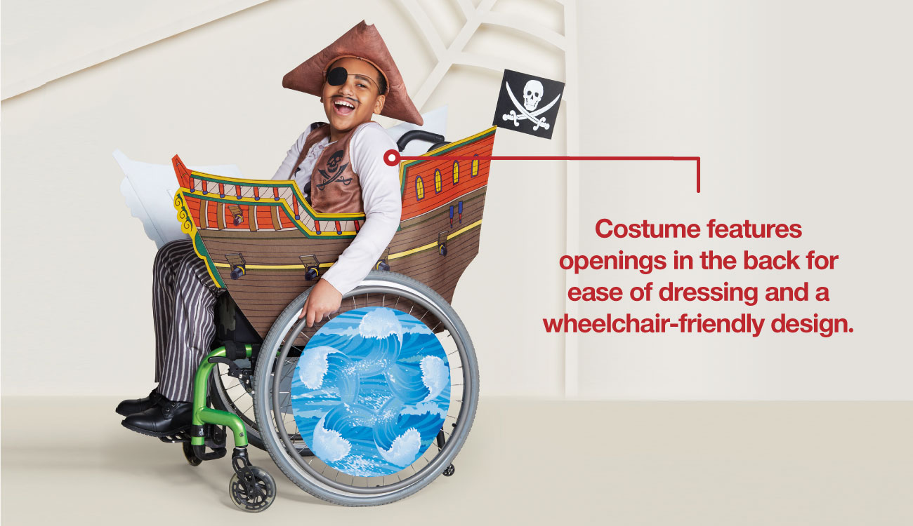 A boy models a pirate costume, his wheelchair decked out like a pirate ship.