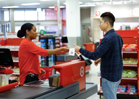 A team member at a staffed checkout lane hands a receipt to a guest.