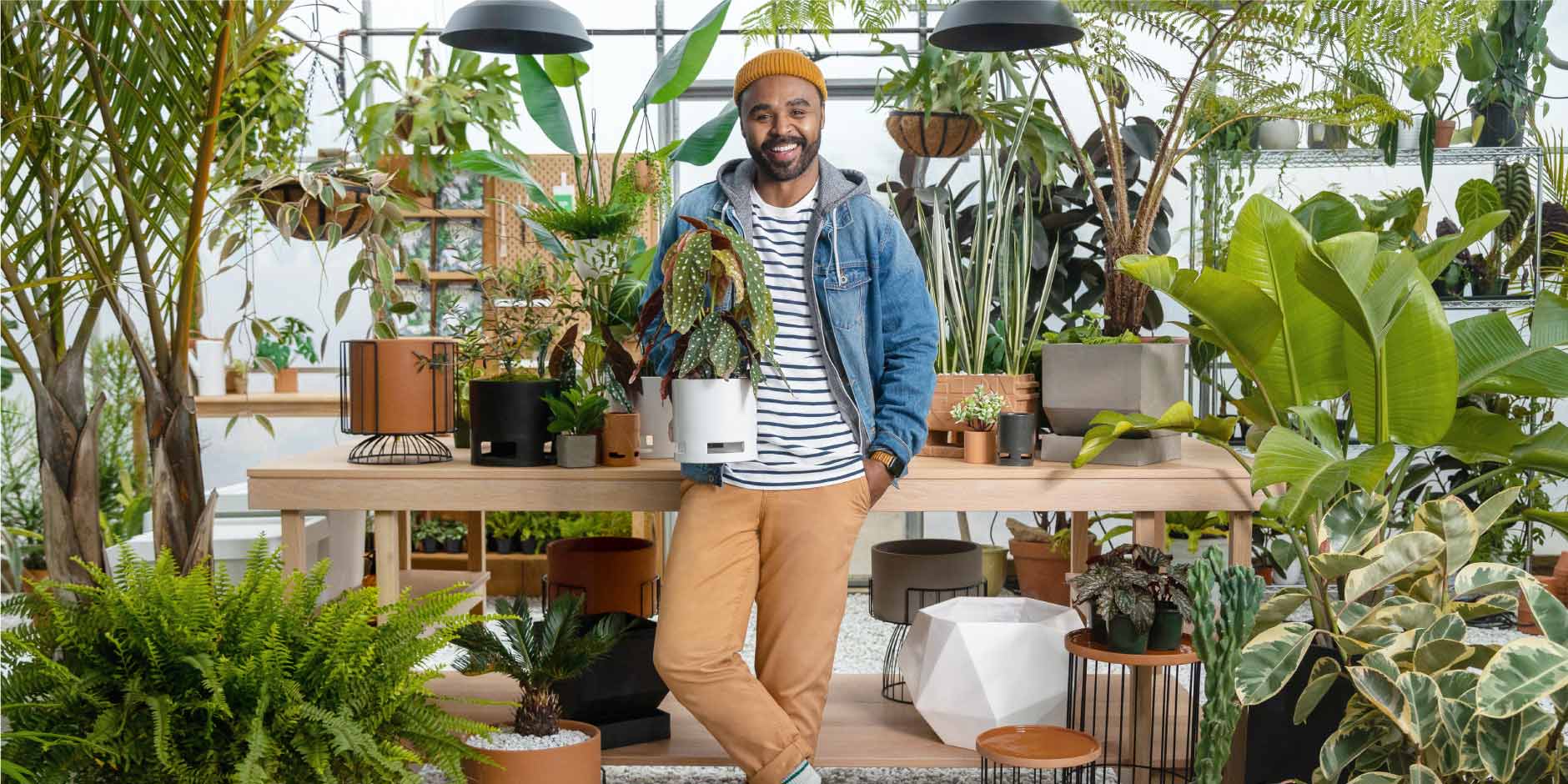 a man standing in a room with plants and a table