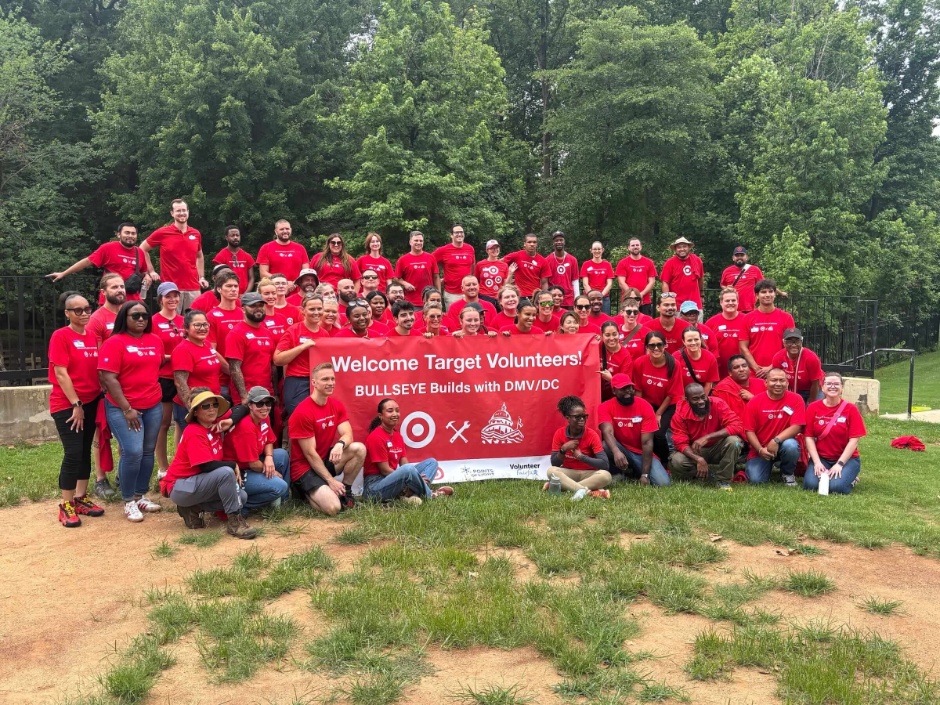 Target team members stand and sit around a banner that says Welcome Target Volunteers! Bullseye Builds with DMV/DC