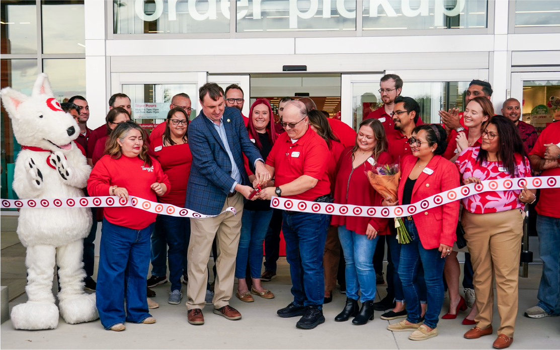 A group of people cut a ribbon outside the doors of a new Target store.
