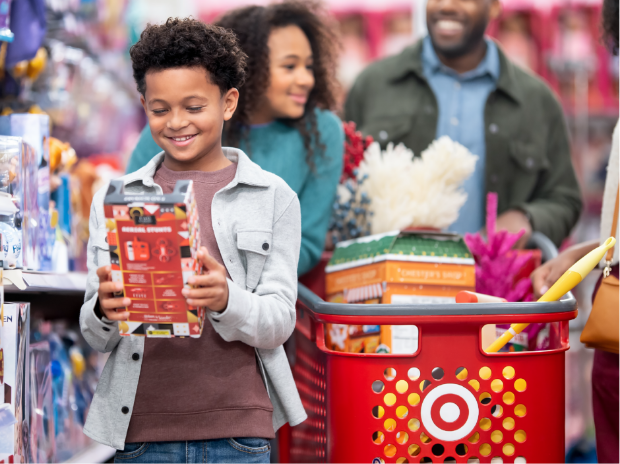 A guest in the foreground holds a package, with a couple pushing a Target cart behind.