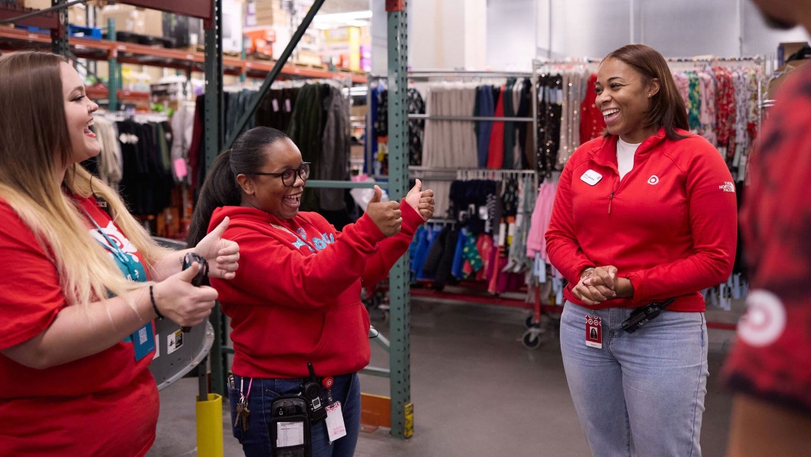 A group of Target team members giving each other a thumbs up as they huddle in the back of the store.