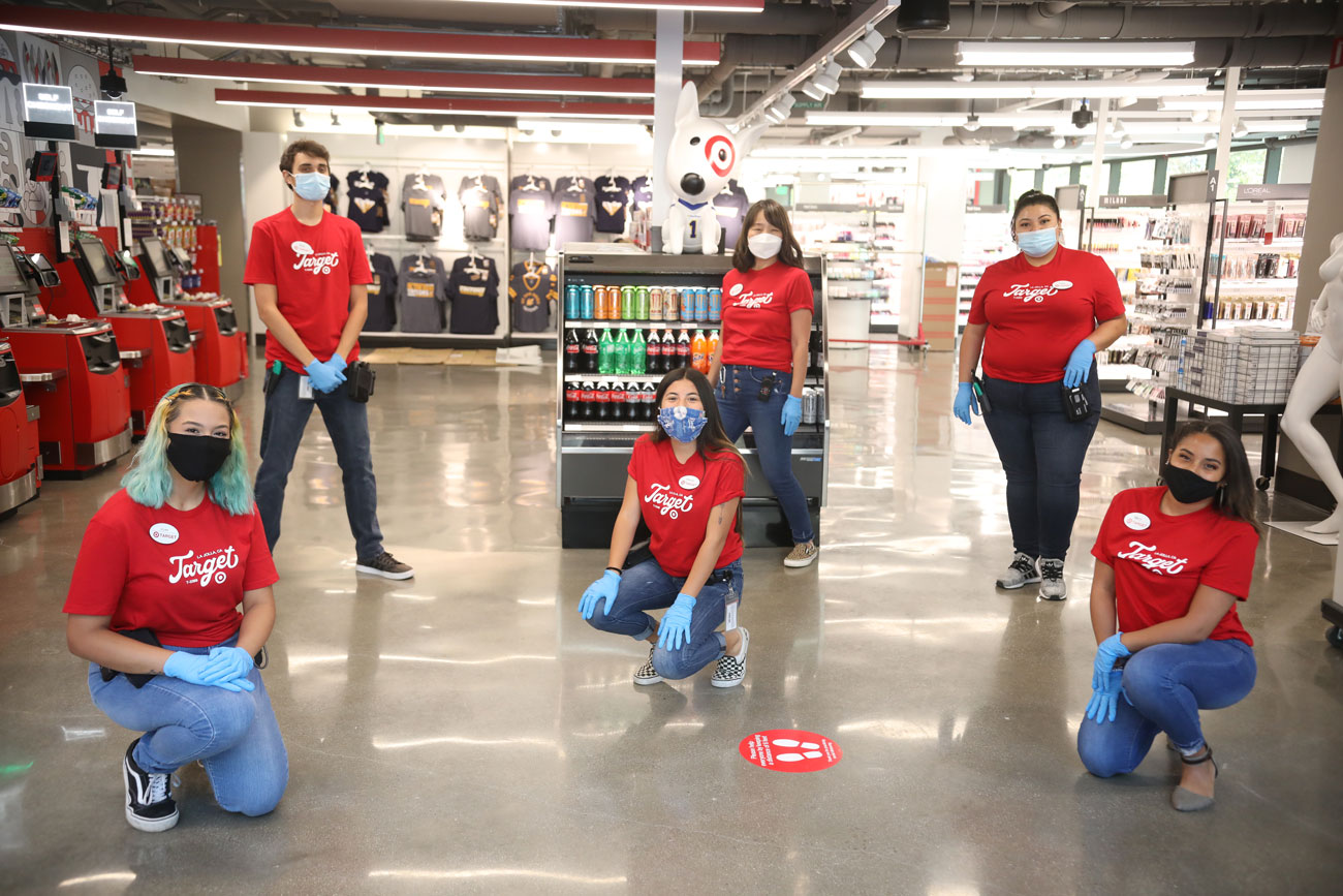 Target team members in matching red shirts and masks and gloves pose for a socially-distant photo