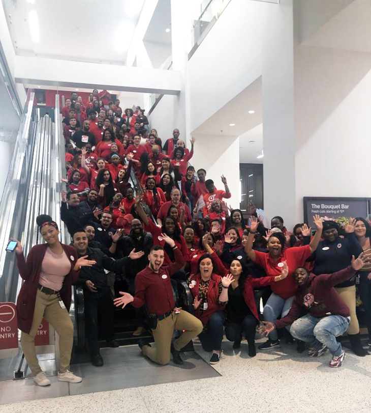 A large group of team members pose on the escalator