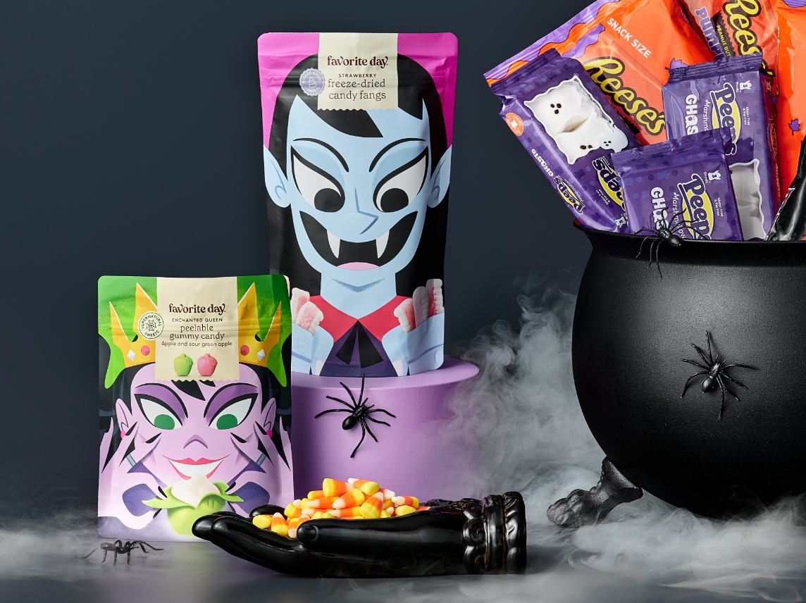 Halloween candy display with Favorite Day monster-themed packs, Reese’s in a cauldron, and candy corn in a skeleton hand
